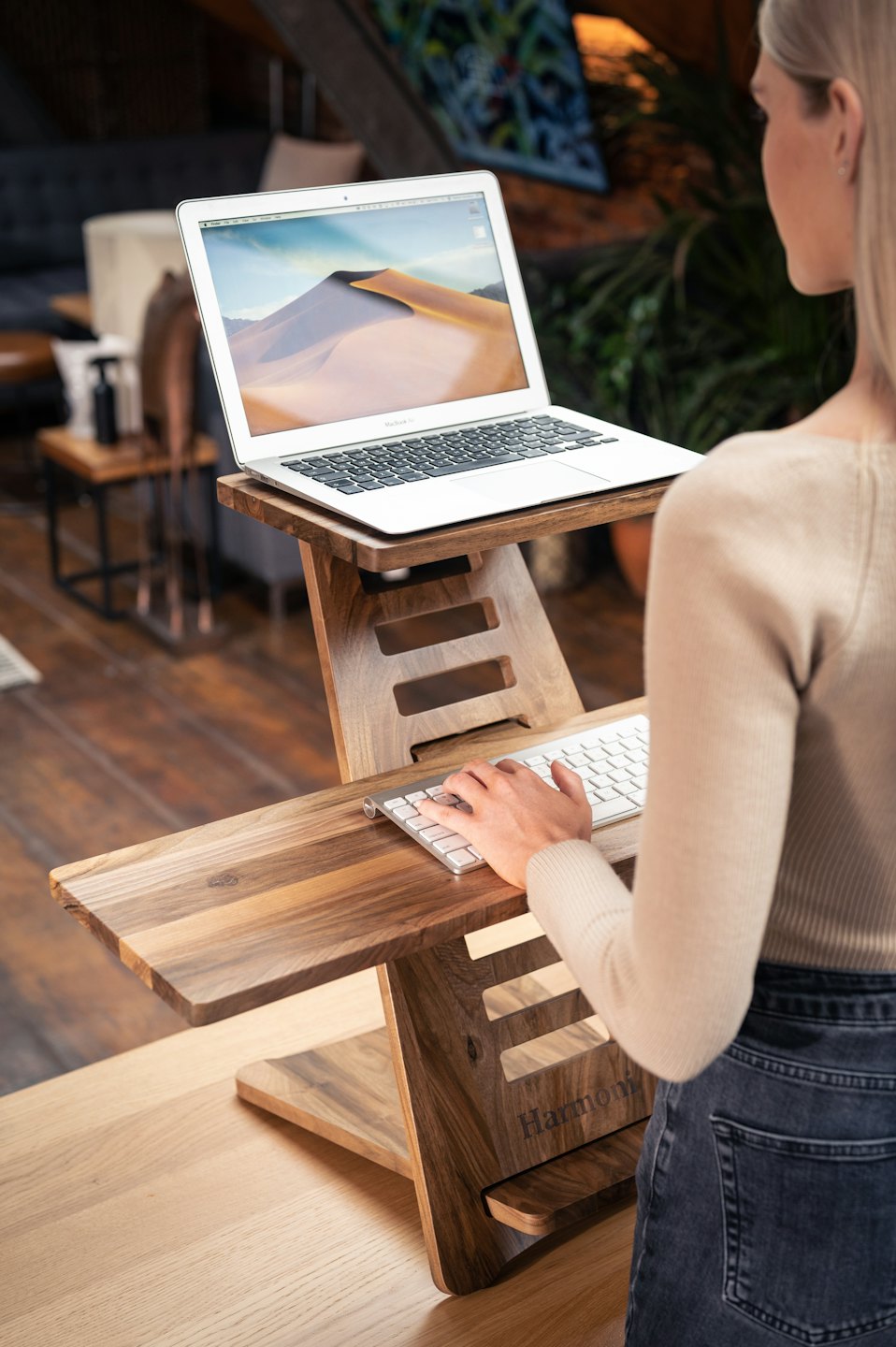 Kobieta pracująca na laptopie przy nakładce na biurko stojącą.